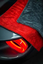 Stacked red and dark gray microfiber cleaning towels with plush pile and stitched edges