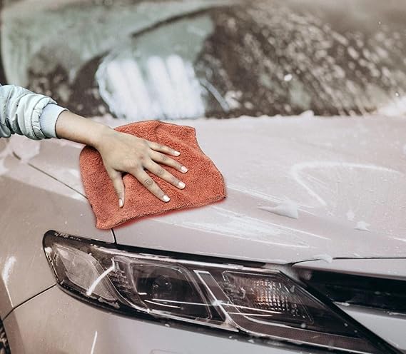 Brown microfiber cleaning cloth being used on a car hood