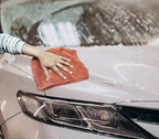 Brown microfiber cleaning cloth being used on a car hood
