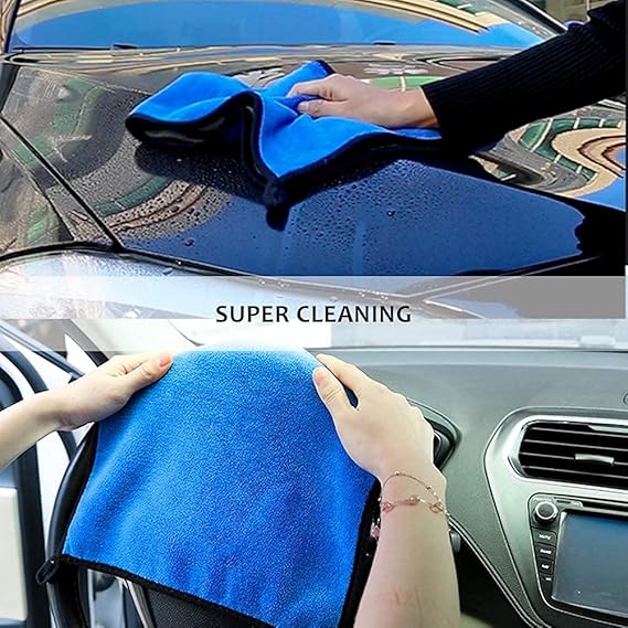 Blue microfiber cloth being pressed onto a car windshield for cleaning