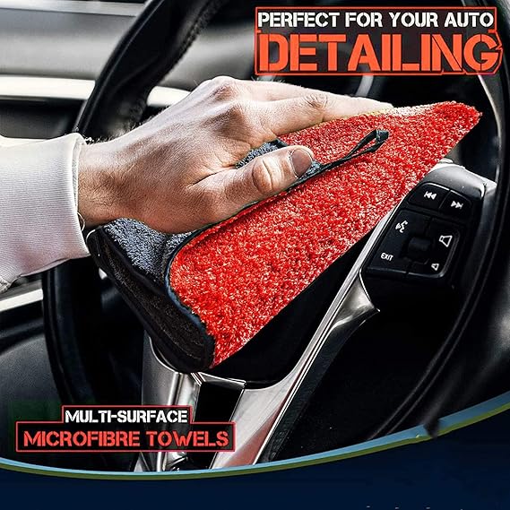 Red and dark gray double-sided microfiber detailing cloth, wiping a car interior surface.